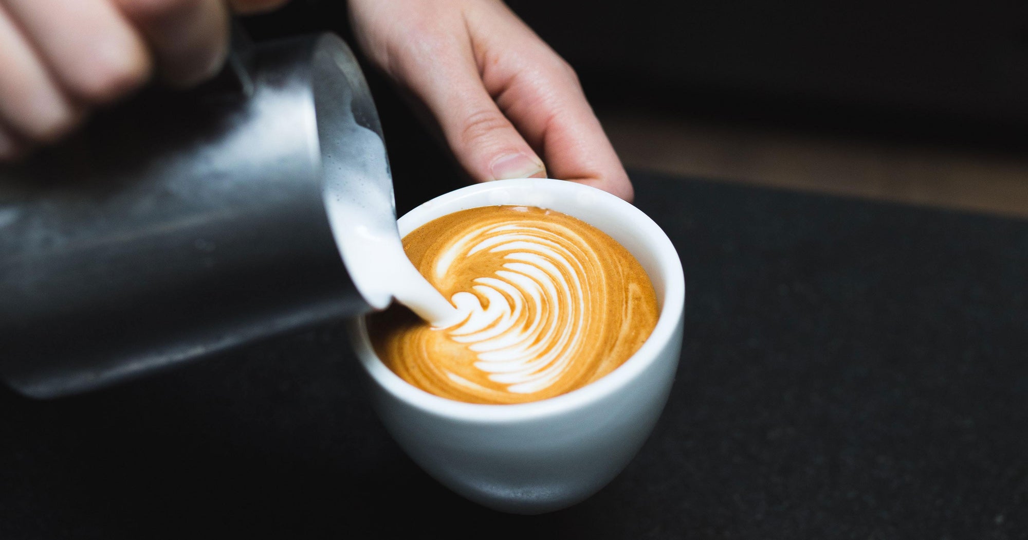 rosetta latte art being poured into a white cup