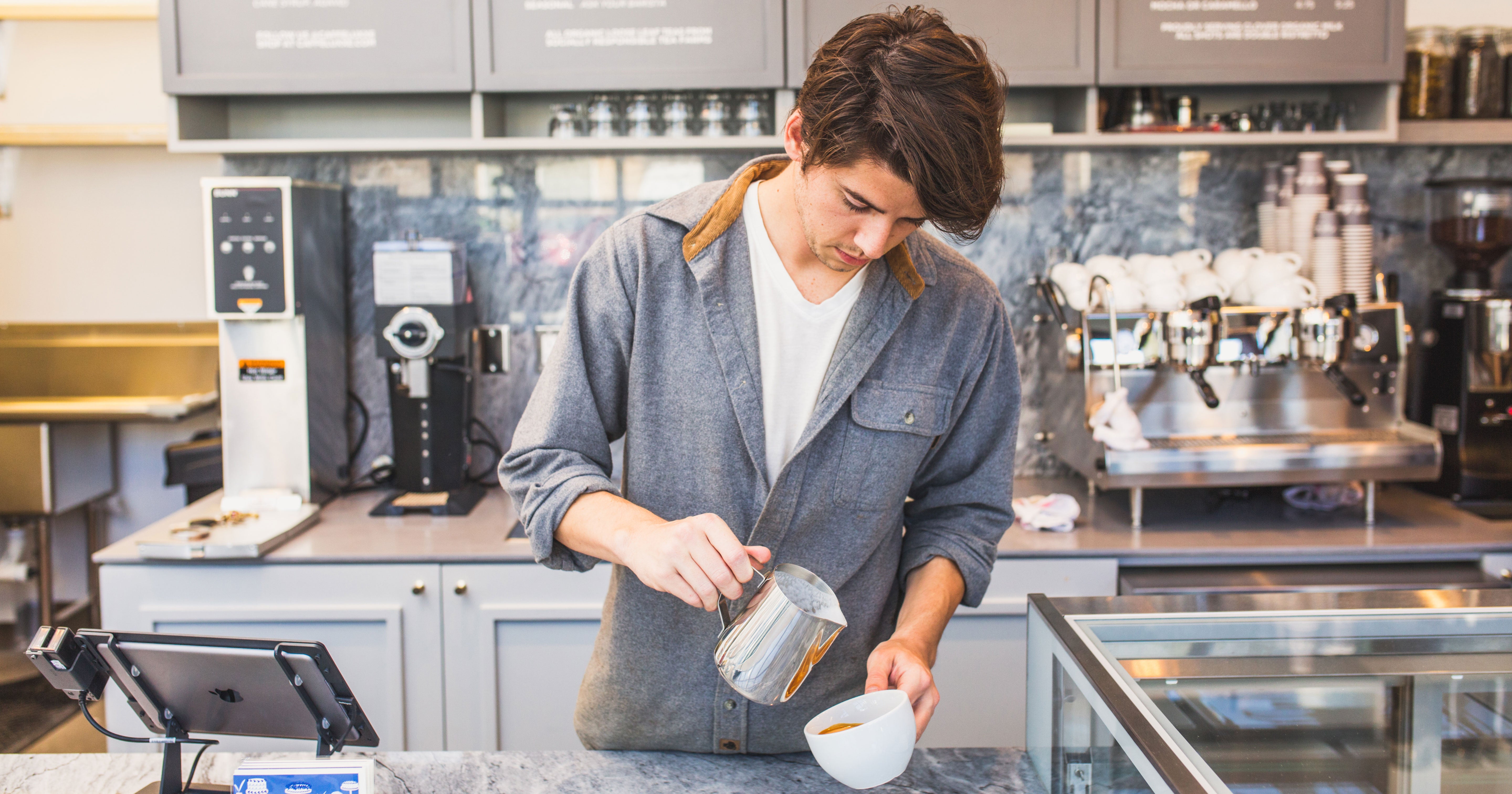 a man pouring a latte at a coffee bar