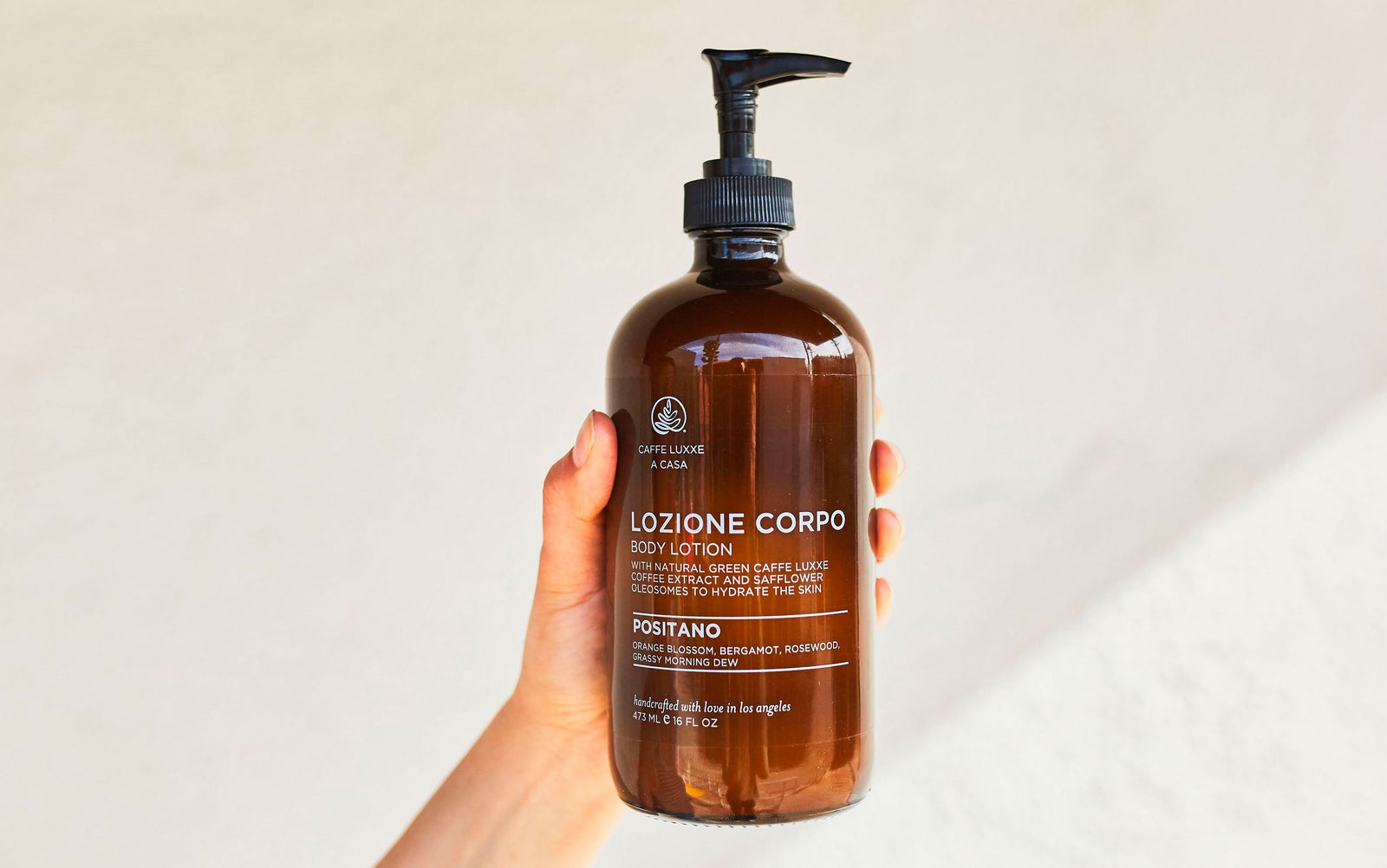 a hand holding a bottle of caffe luxxe a casa positano scented body lotion