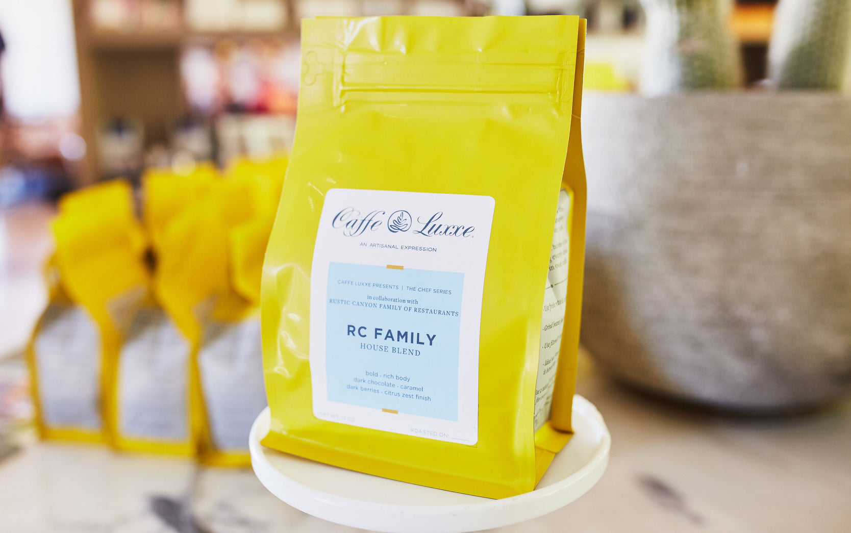 a close up of a bag of RC Family blend, which is sitting a top a small white cake stand