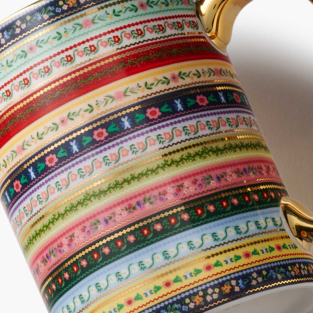 Decorative cup with colorful striped pattern and gold accents