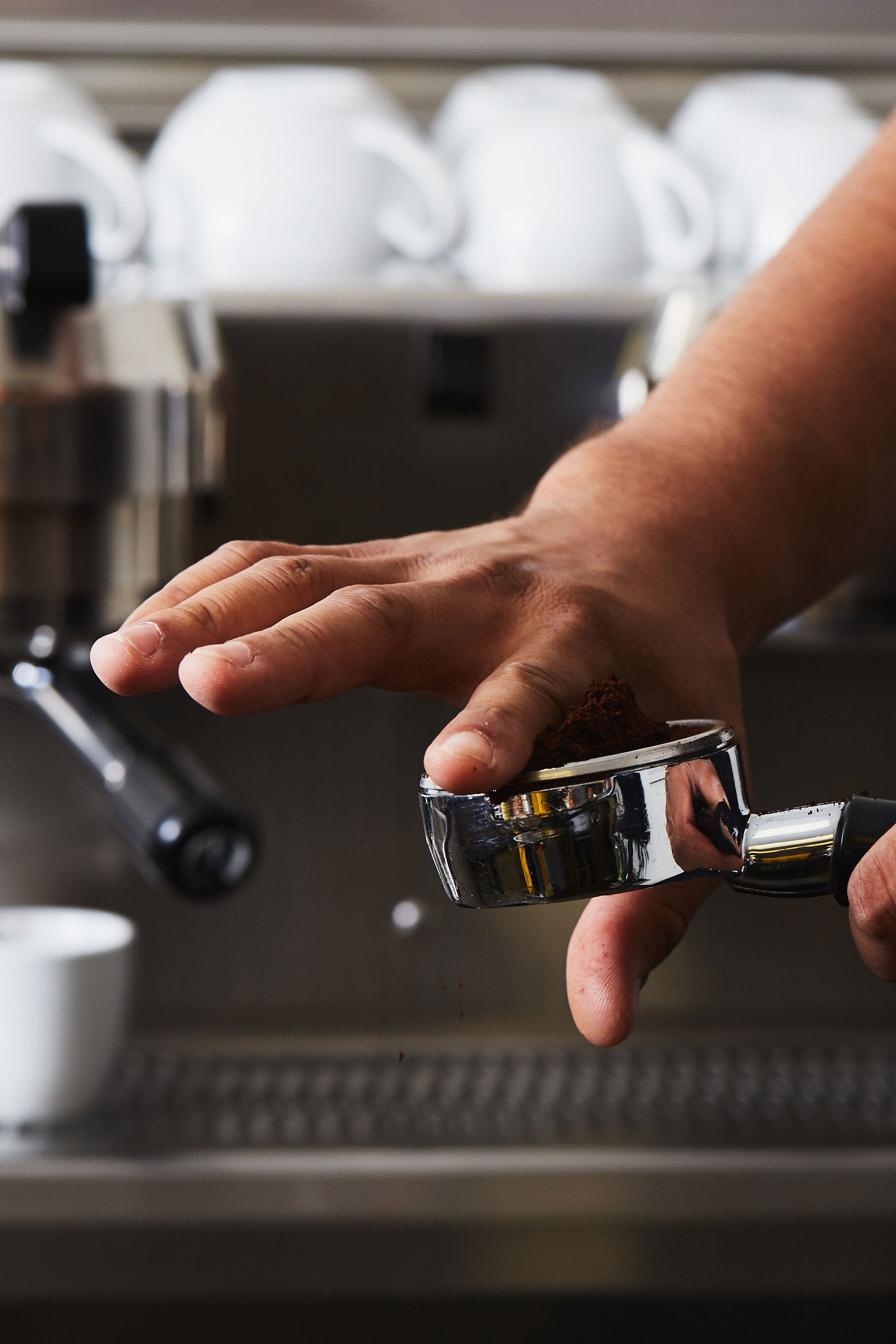 a hand distributing coffee from a bottomless portafilter