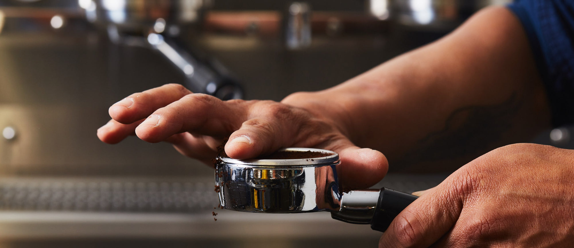 a hand distributing coffee from a bottomless portafilter
